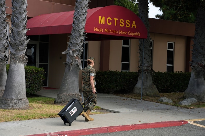 A Marine carries a piece of equipment into MCTSSA headquarters.