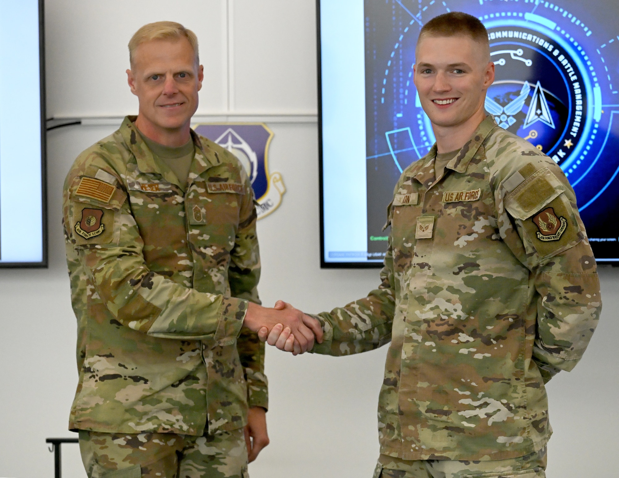 Two men wearing Air Force fatigues, shaking hands.