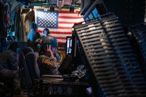 An Airman dons a helmet at a weapons station on an AC-130J