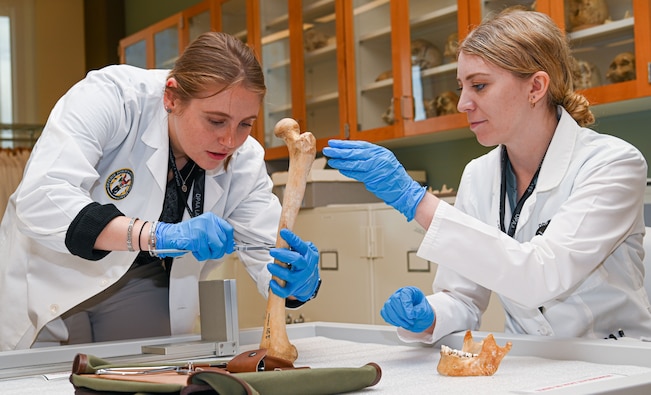 Sydney Martin, left, and Giulia Dunn, DPAA forensic anthropologists measure a replica bone at the Daniel K. Inouye DPAA Center of Excellence, Joint Base Pearl Harbor-Hickam, Sept. 12, 2025.