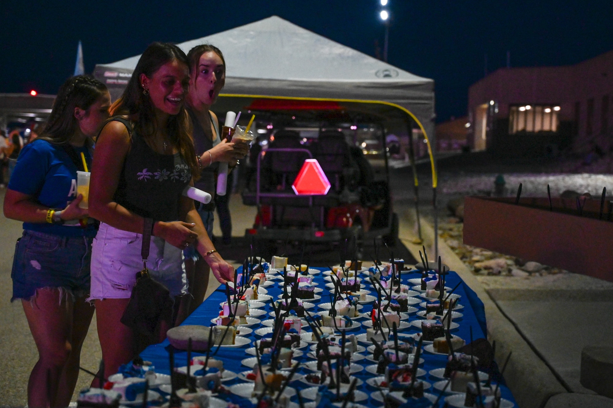 Attendees of Summer Bash stand near a table with slices of cake in celebration of the Air Force birthday during Summer Bash at Laughlin Air Force Base, Texas, Sept. 15, 2025. In place of a traditional Air Force Ball, LAFB celebrated the service’s 78th birthday with a cake-cutting ceremony and free cake for attendees. (U.S. Air Force photo by Senior Airman Jarrett Smith)
