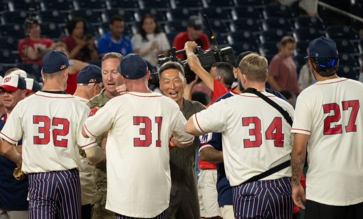 U.S. Air Force Col. Jun S. Oh, 316th Wing and installation commander, and Chief Master Sgt. Kevin Helms, 316th Wing command chief, embrace the Joint Base Andrews softball team after the championship game of Battle of the Bases at Nationals Park, Washington, D.C., Sept. 13, 2025.