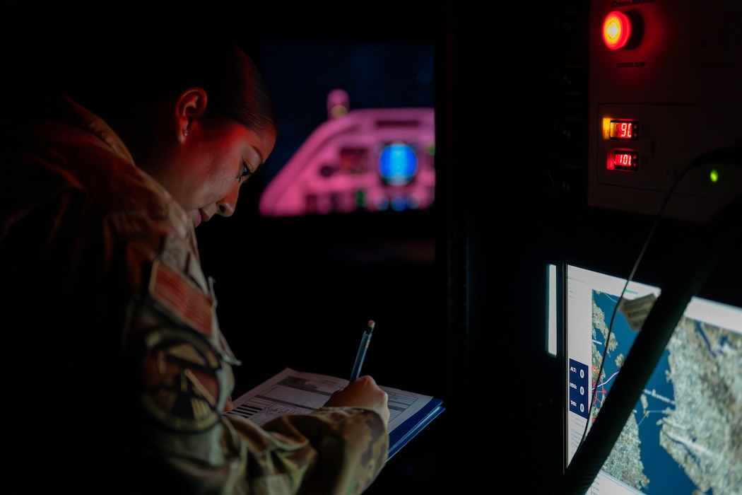 Airman takes notes in dark room during hypoxia training