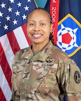 Photo of Command Sgt. Maj. Marla Darby wearing combat uniform in front of the U.S. Flag and an organizational flag.