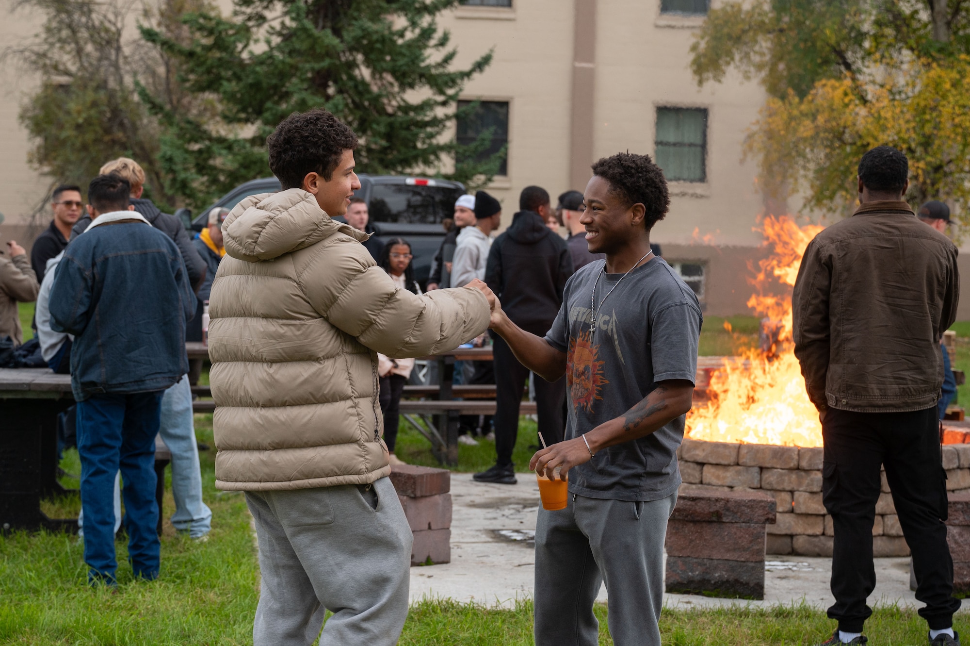 U.S. Air Force Airman 1st Class Ethan Bonilla, 356th Fighter Generation Squadron crew chief, and Airman 1st Class Zion Askin, 354th Medical Group laboratory technician, shake hands during the one-year anniversary of Holy Smokes at Eielson Air Force Base, Alaska, Sept. 12, 2025.