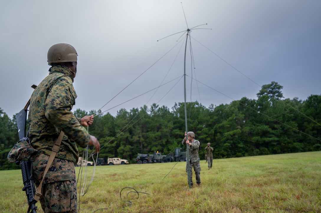 U.S. Marine Corps Lance Cpl. Roderick Meadows, left, a transmissions system operator with 2nd Combat Readiness Regiment, 2nd Marine Logistics Group, sets up an OE254 antenna during a regimental field exercise at Marine Corps Base Camp Lejeune, North Carolina, Sept. 15, 2025. The REGFEX conducted by 2nd CRR is a large-scale training event designed to improve and sustain the regiment’s capability to deliver intermediate-level supply and maintenance support to II Marine Expeditionary Force, ensuring operational readiness in austere and expeditionary environments. Meadows is a native of Florida. (U.S. Marine Corps photo by Lance Cpl. Brady V. Hathaway)