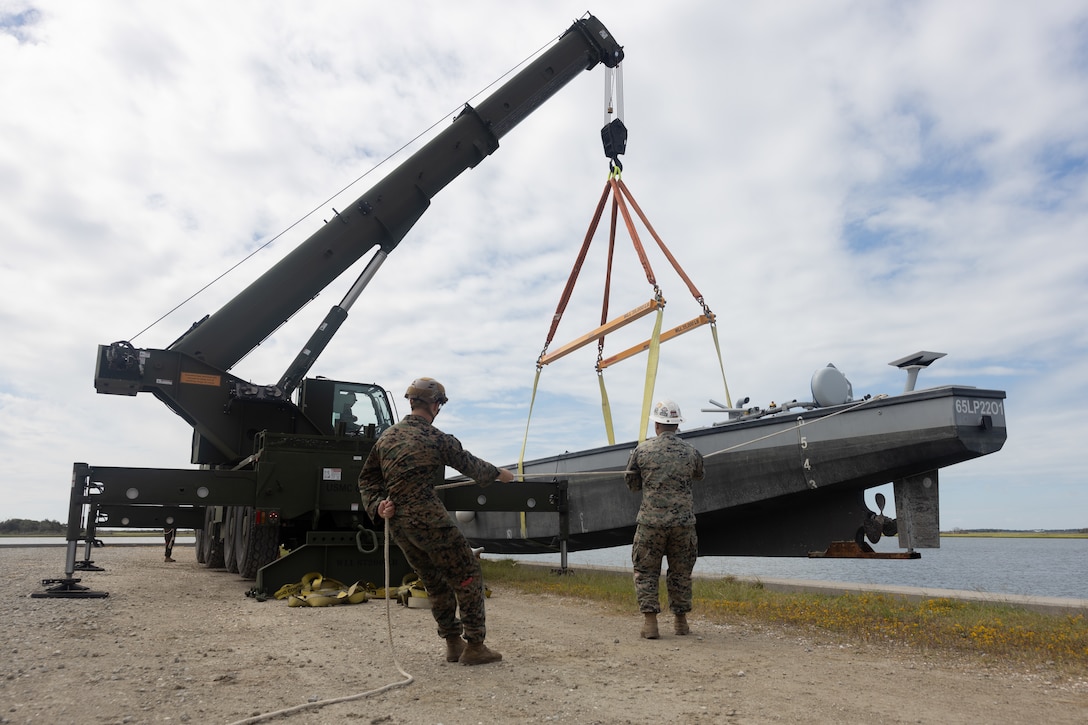 U.S. Marines with Maritime Distribution Platoon, 2nd Distribution Battalion, 2nd Marine Logistics Group, lower an autonomous low-profile vessel into the water during exercise UNITAS 2025 at Marine Corps Base Camp Lejeune, North Carolina, Sept. 15, 2025. 2nd MLG is working with the Marine Corps Warfighting Lab to experiment with the ALPV for a more lethal, agile, and resilient capability while conducting expeditionary advanced base operations. UNITAS, which is Latin for “unity,” was conceived in 1959 and has taken place annually since first conducted in 1960. This year marks the 66th iteration of the world’s longest running annual multinational maritime exercise. The exercise trains forces in joint maritime operations that enhance tactical proficiency and increase interoperability with the presence of unmanned air, surface and submarine systems. (U.S. Marine Corps photo Lance Cpl. Franco Lewis)