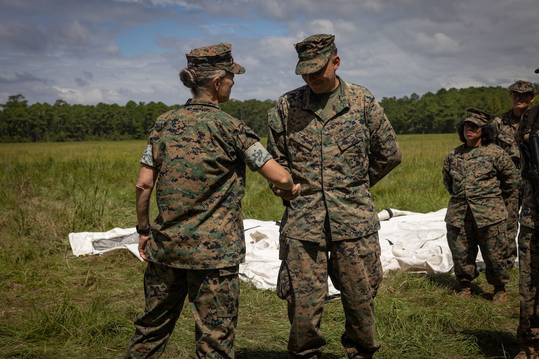 U.S. Marine Corps Brig. Gen. Maura M. Hennigan, 2nd Marine Logistics Group commanding general, left, presents Lance Cpl. Gabriel Jacobs, a logistics specialist with 2nd Combat Readiness Regiment, 2nd MLG, with a challenge coin at Marine Corps Base Camp Lejeune, North Carolina, Sept. 15, 2025. Hennigan presented challenge coins to Marines participating in 2nd CRR’s regimental field exercise for their excellence and tactical expertise in their military occupational specialties. (U.S. Marine Corps photo by Sgt. Makayla Elizalde)