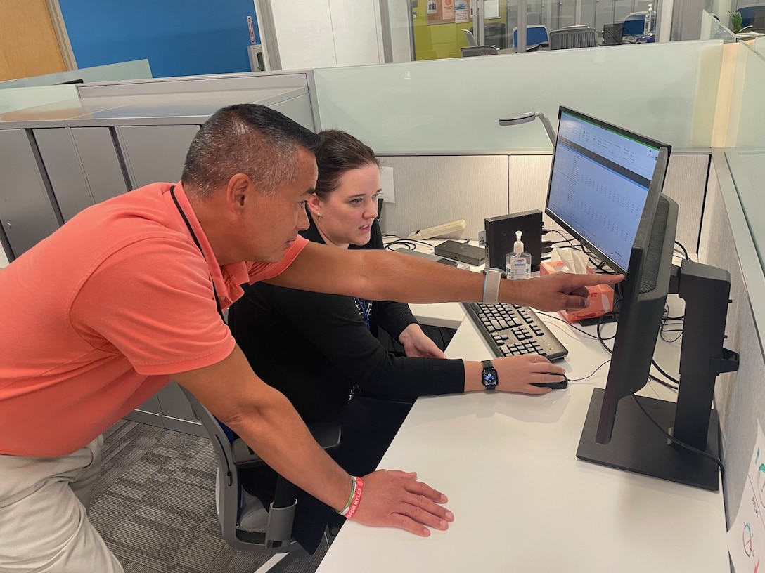 Two people work deskside at a computer.