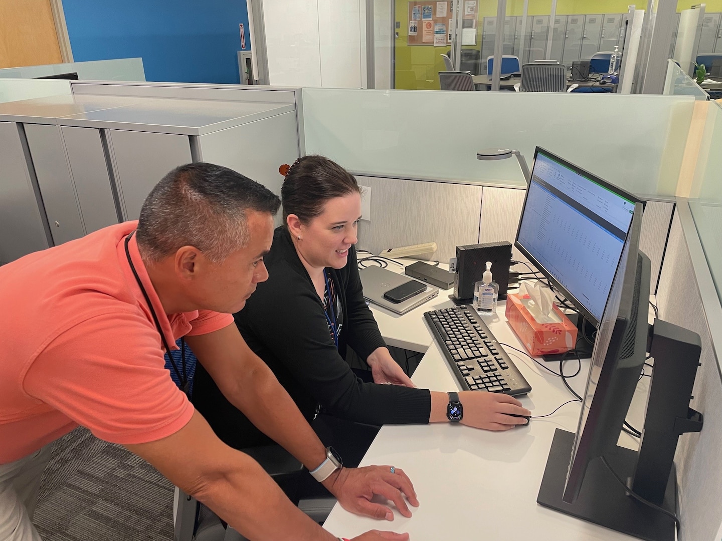 Two people work deskside at a computer.
