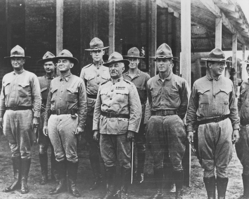 Marines standing in uniform pose for a photo outside.