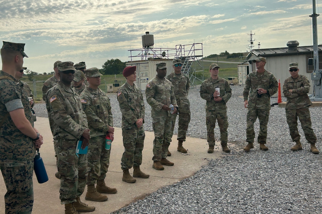 Several people in military camouflage uniforms gather in a semicircle.