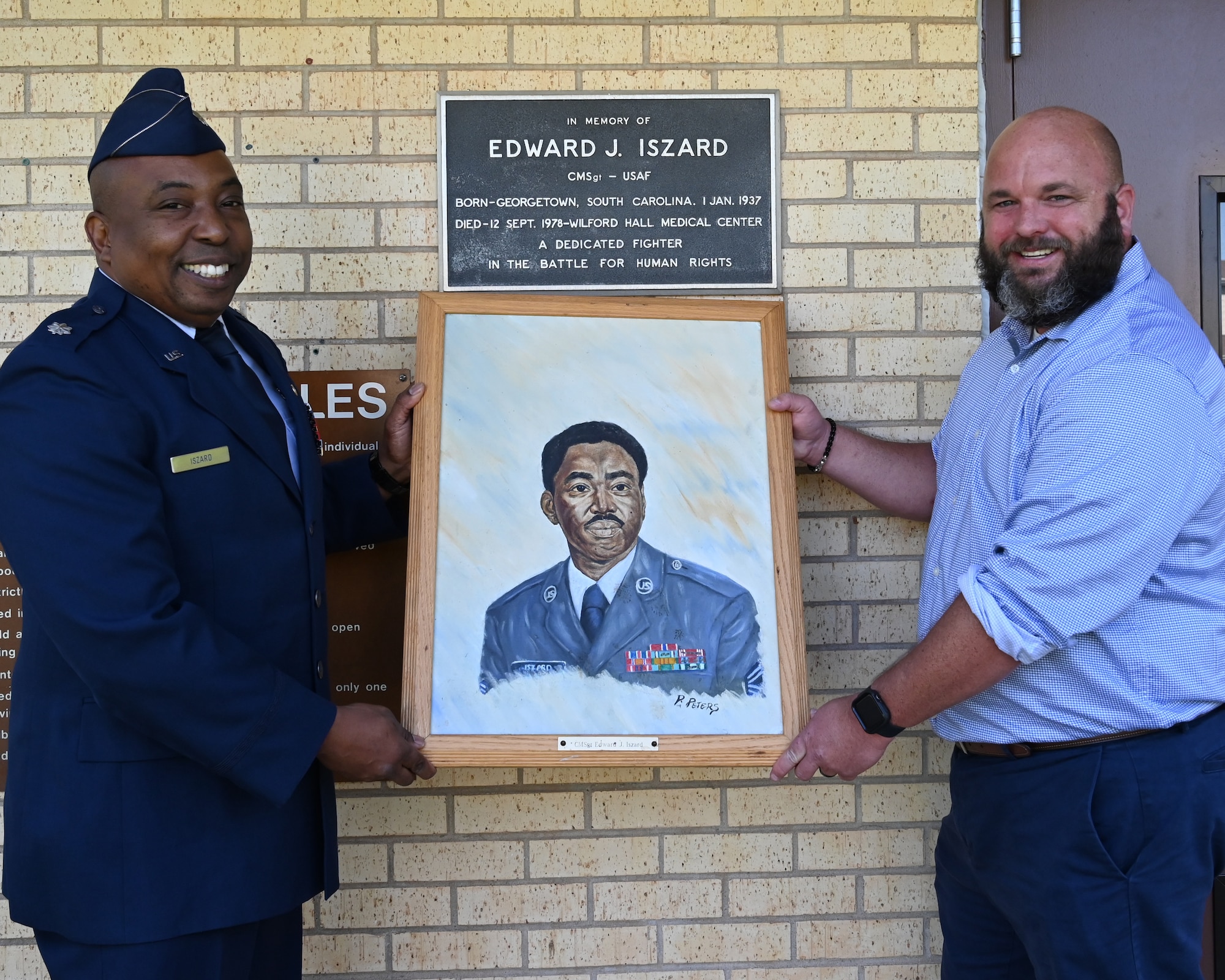 Two men holding a painting, standing at the pool facility at Tinker AFB.