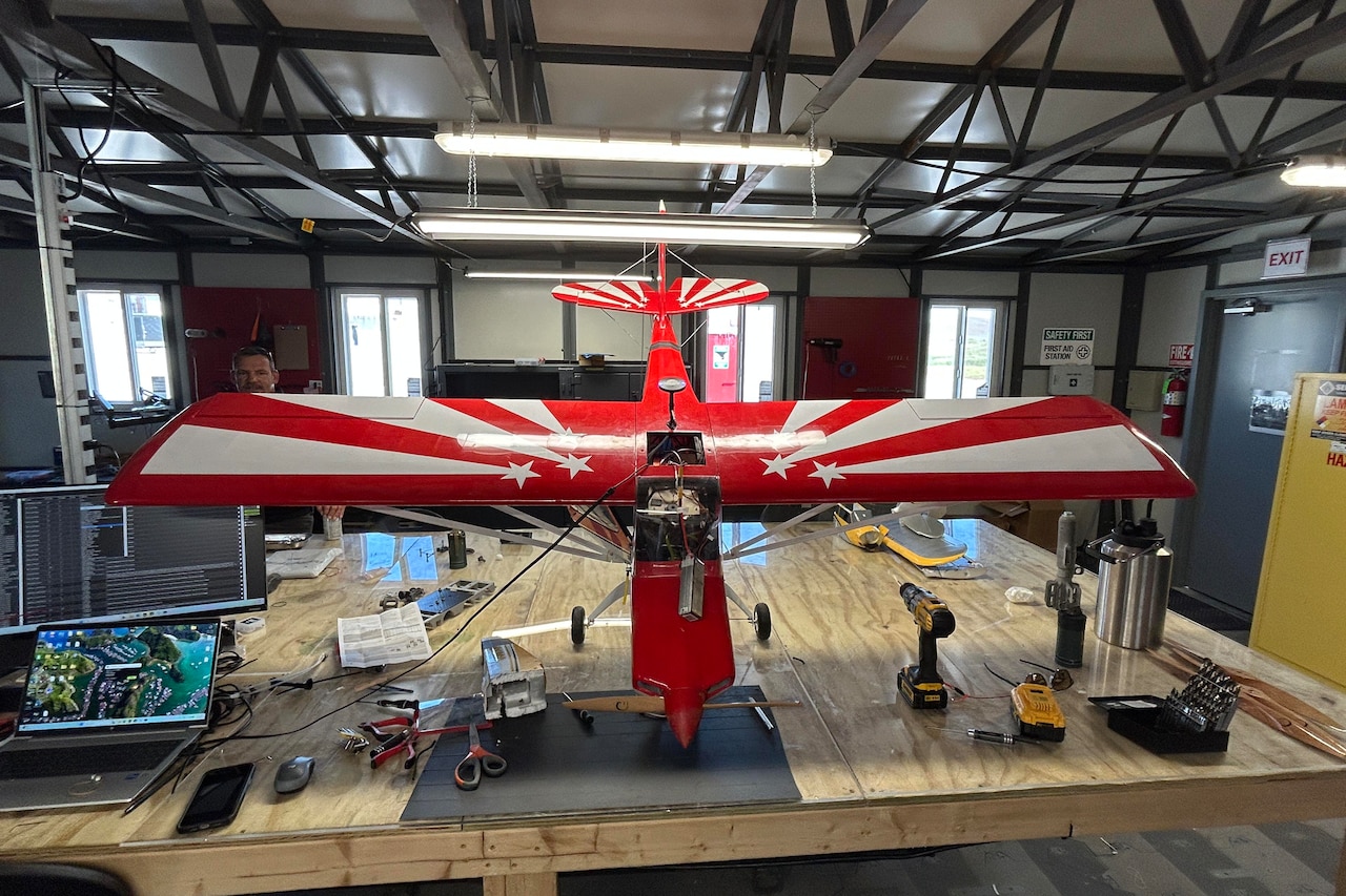 A large drone that looks like a small airplane sits atop a wooden table.