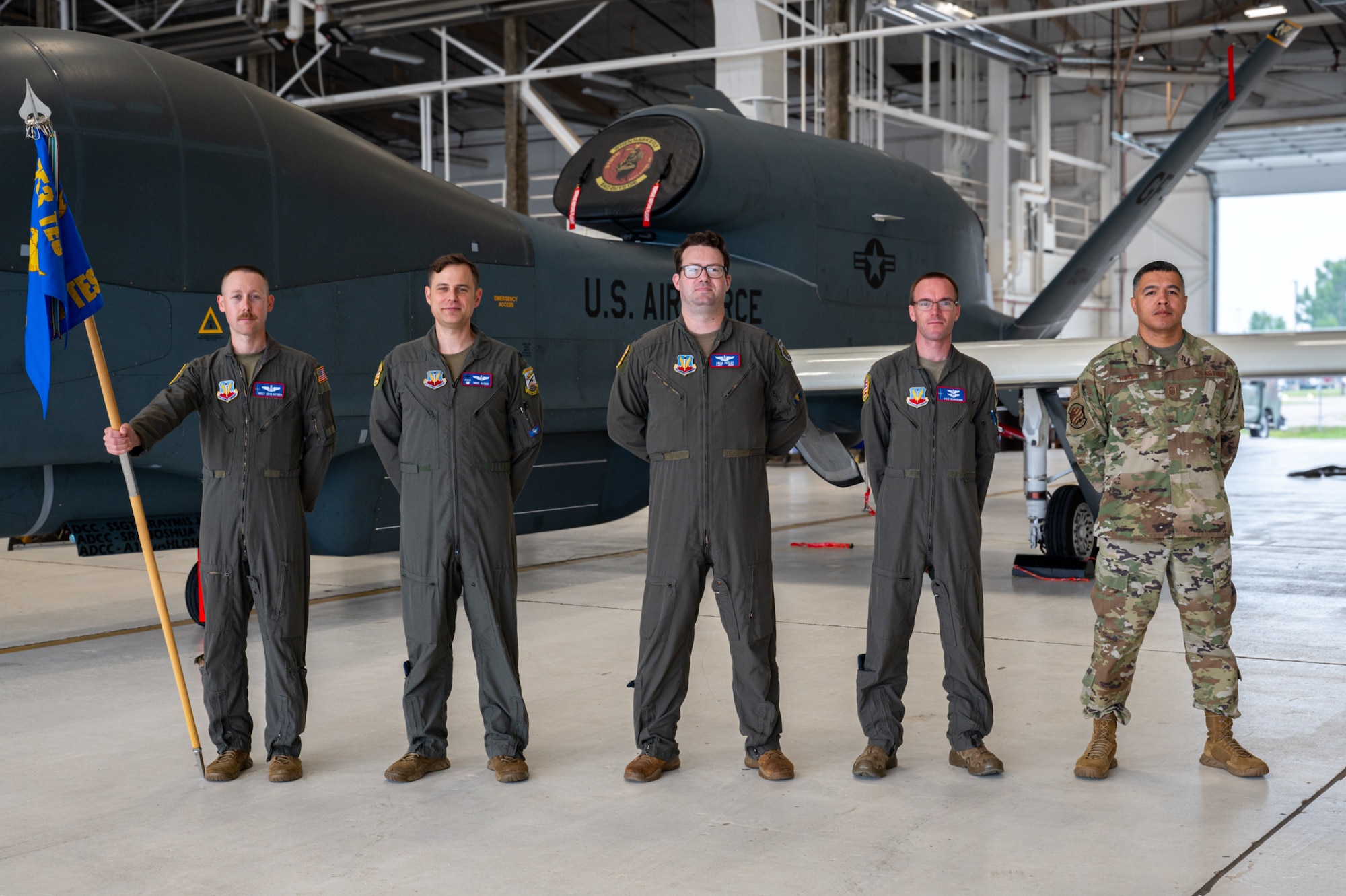 A photo of 5 men standing in from of a plane.