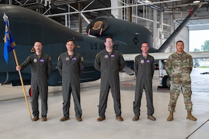 A photo of 5 men standing in from of a plane.