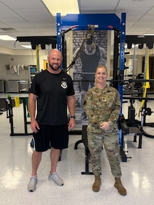 two members of the 78th Operational Medical Readiness Squadron Operational Support team pose in front of gym equipment