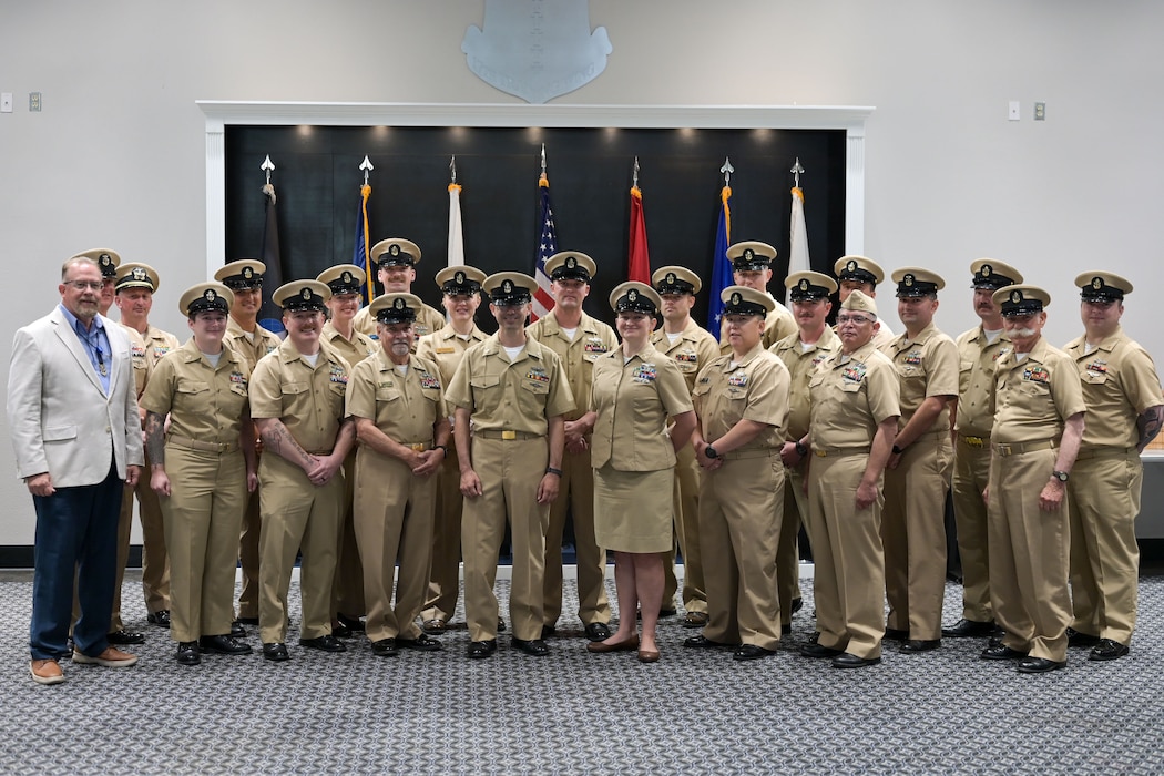 A group of Navy Chiefs stand for a group picture inside a