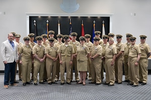 A group of Navy Chiefs stand for a group picture inside a