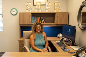 A woman poses for a photo at a her desk.