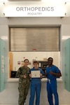 The Orthopedics department of U.S. Naval Hospital Guam is recognized by the Military Health System Joint Outpatient Experience Survey and is awarded for 100% Satisfaction for Fiscal Year 2025 Quarter 2. From left to right: Hospital Corpsman 3rd Class (HM3) Tran Ly, HM3 Sophia Anderson, Hospital Corpsman 2nd Class (HM2) Bernard Claxton, all orthopedics technicians at USNH Guam.