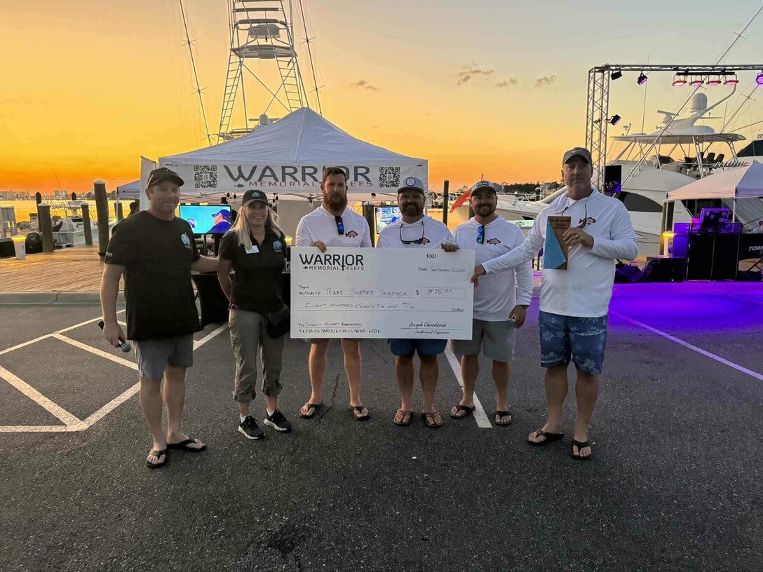 Picture of a group holding up a check from a Fishing Tournament.