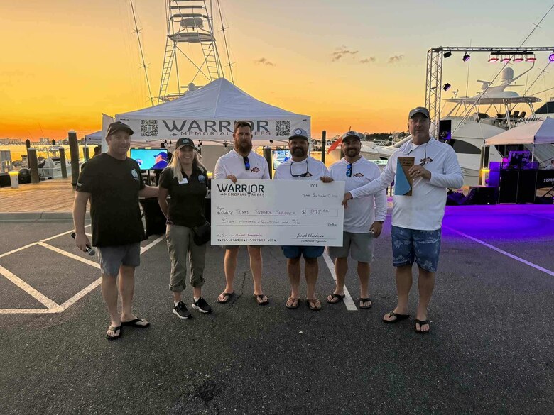 Picture of a group holding up a check from a Fishing Tournament.