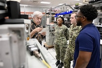 Inside a well-equipped laboratory, a Navy instructor provides guidance to a sailor working on electronic equipment. This image depicts the hands-on training environment at NIWC Atlantic designed to improve radio communication skills.