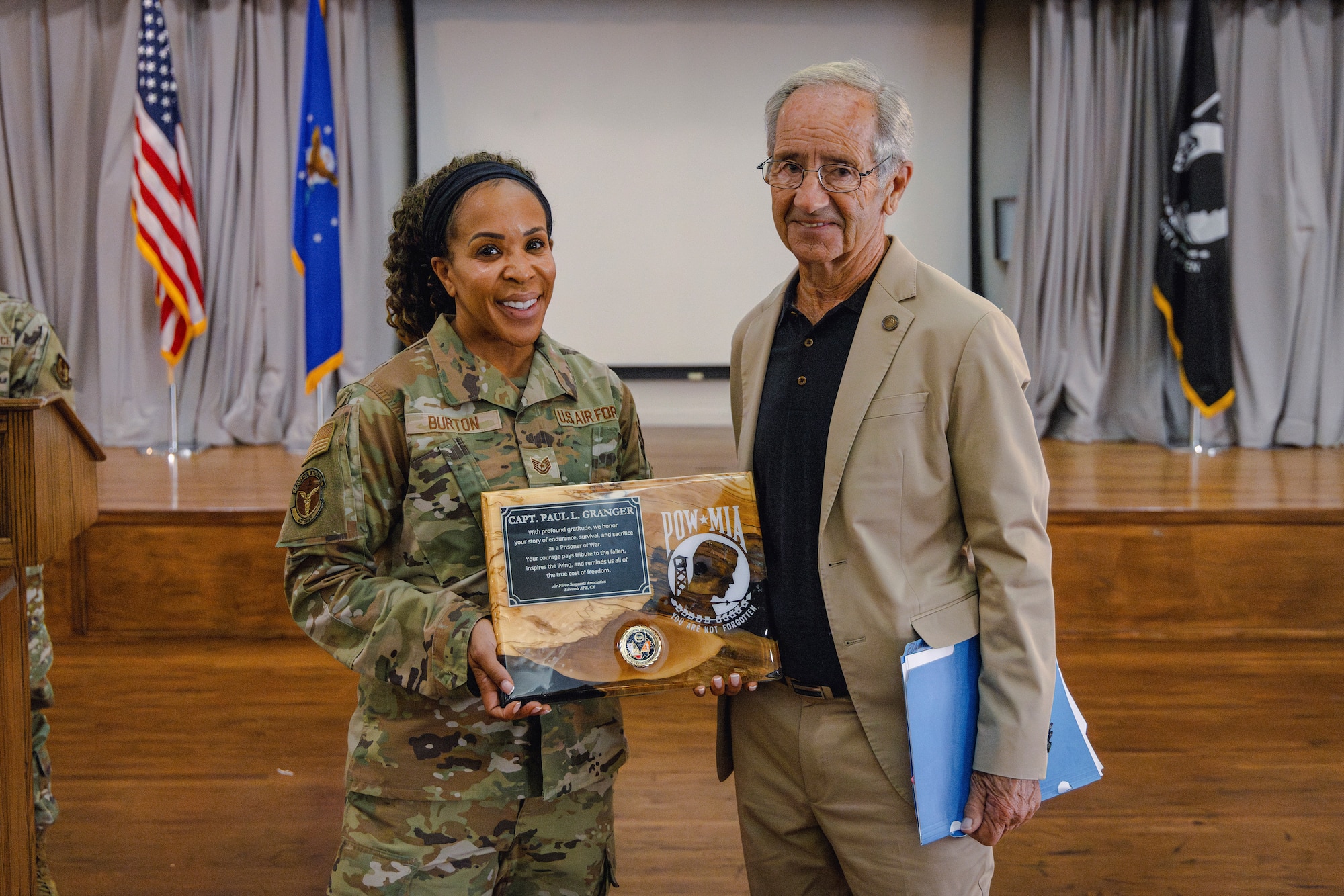Tech. Sgt. Halima Burton, 412th Medical Group, presents a plaque to retired Capt. Paul Granger, a Vietnam War veteran and POW survivor, Sept. 12. Granger shared his story of survival, resilience and reintegration in honor of POW/MIA Recognition Day, Sept. 19. (Air Force photo by Brandon Hernandez)