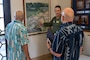 A U.S. Air Force Airmen shows two civilians a painting depicting the history of Joint Base Pearl Harbor-Hickam, Hawaii.