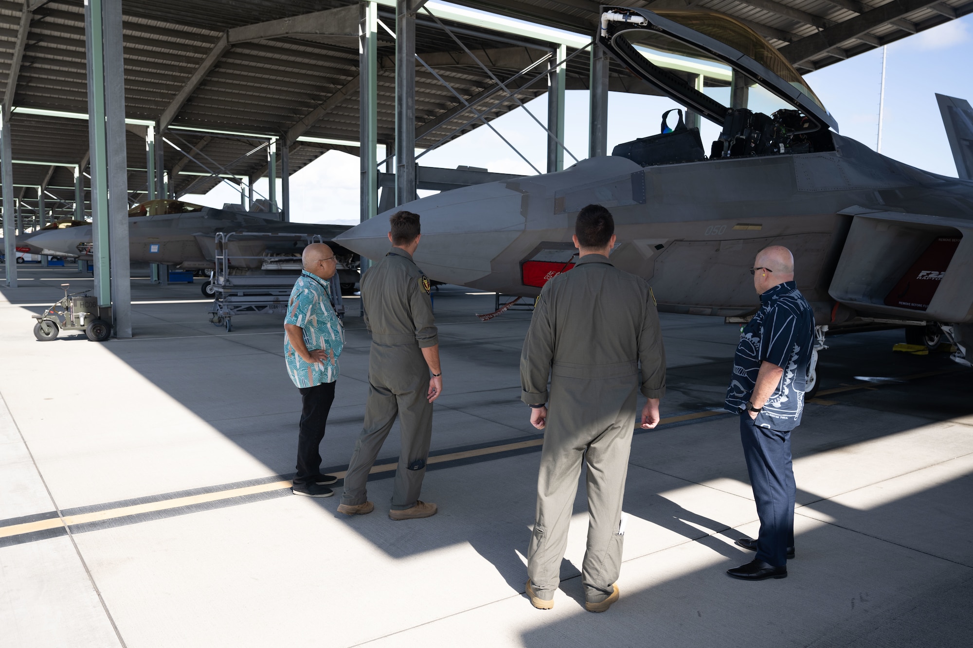 Two U.S. Air Force pilots show civilians around an F-22 raptor on the flightline of Joint Base Pearl Harbor-Hickam, Hawaii.