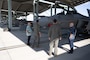 Two U.S. Air Force pilots show civilians around an F-22 raptor on the flightline of Joint Base Pearl Harbor-Hickam, Hawaii.
