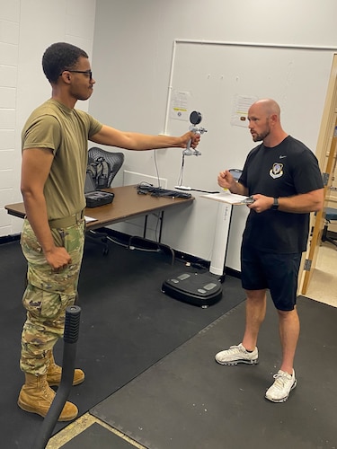 an airman grips a pinch gauge while a coach reads the results