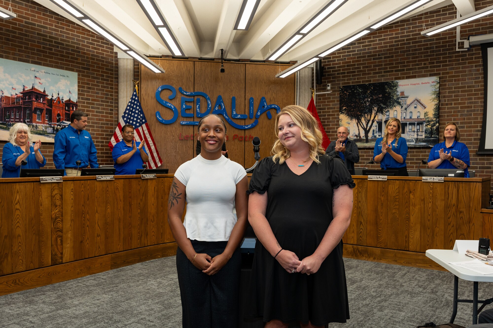 U.S. Air Force Senior Airman Jada McMillan, 509th Operational Medical Readiness Squadron medical technician, left, and Darci Curtis, 509th Healthcare Operations Squadron pharmacy technician, are applauded during a city council meeting in Sedalia, Missouri, Sept. 2, 2025.