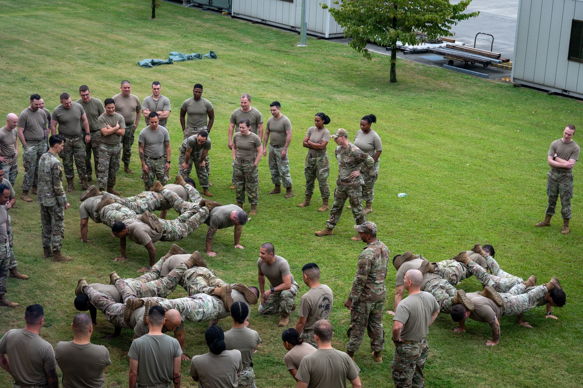 A group of servicemembers perform four-men pushups