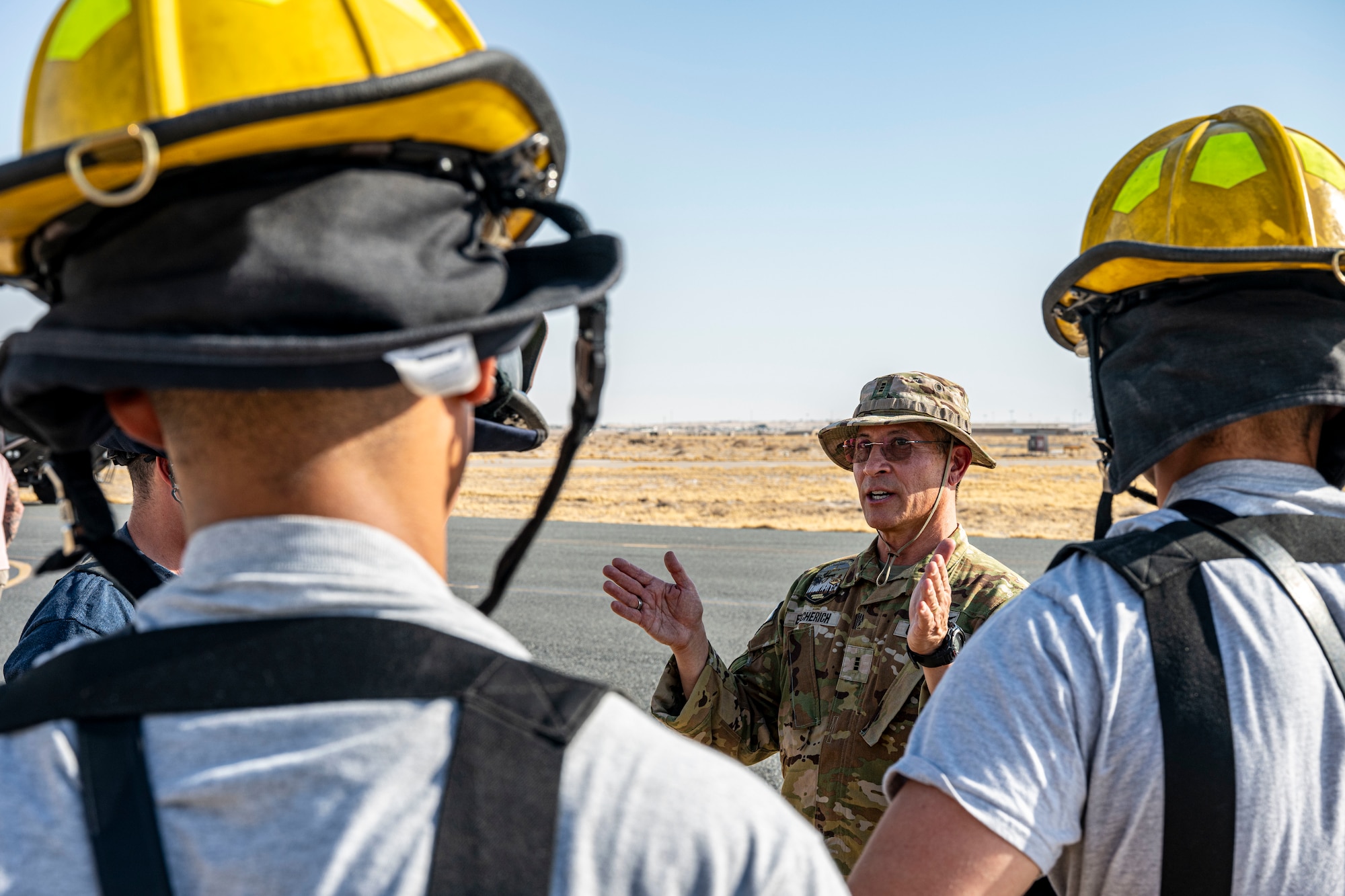 Warrant Officer Mark Escherich is in the background between the shoulders of firefighters in the foreground listening to him dicuss procedures