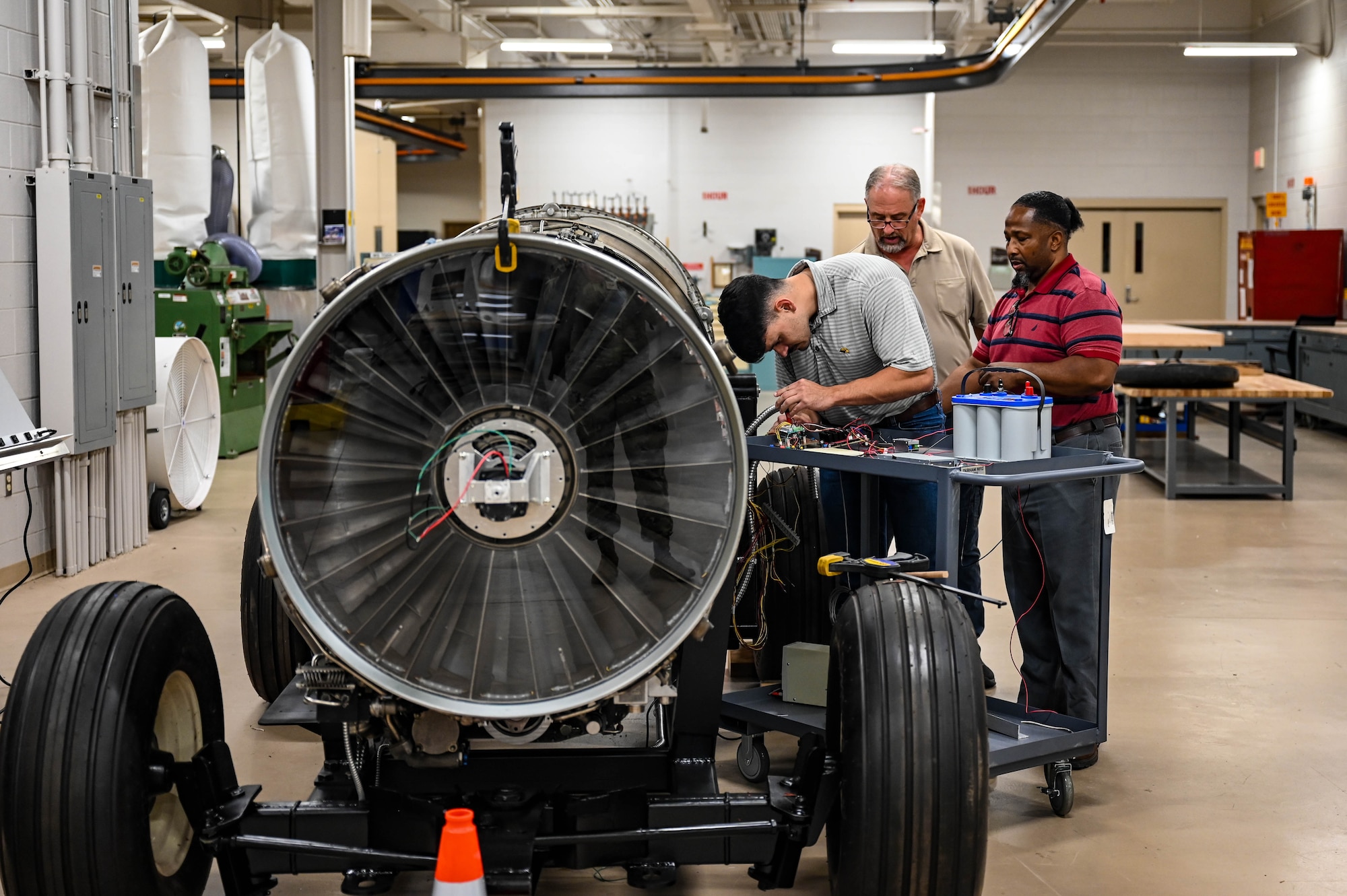 Three men work on a plane engine display