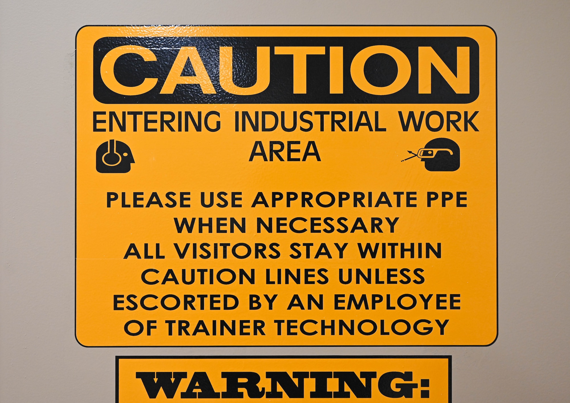 A yellow caution sign warns people they are entering an industrial work zone.