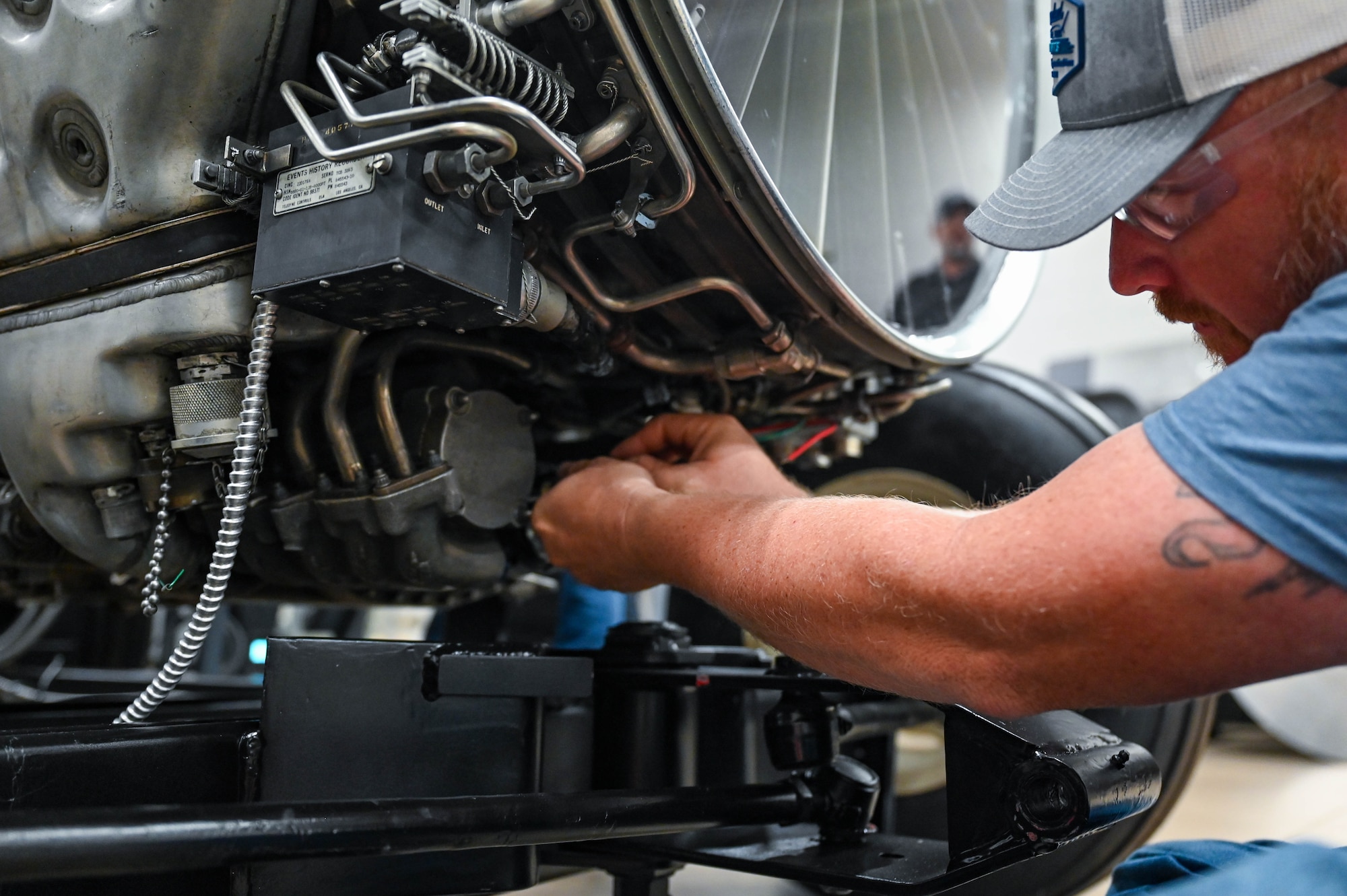 A man installs a drive motor underneath a plane display engine.