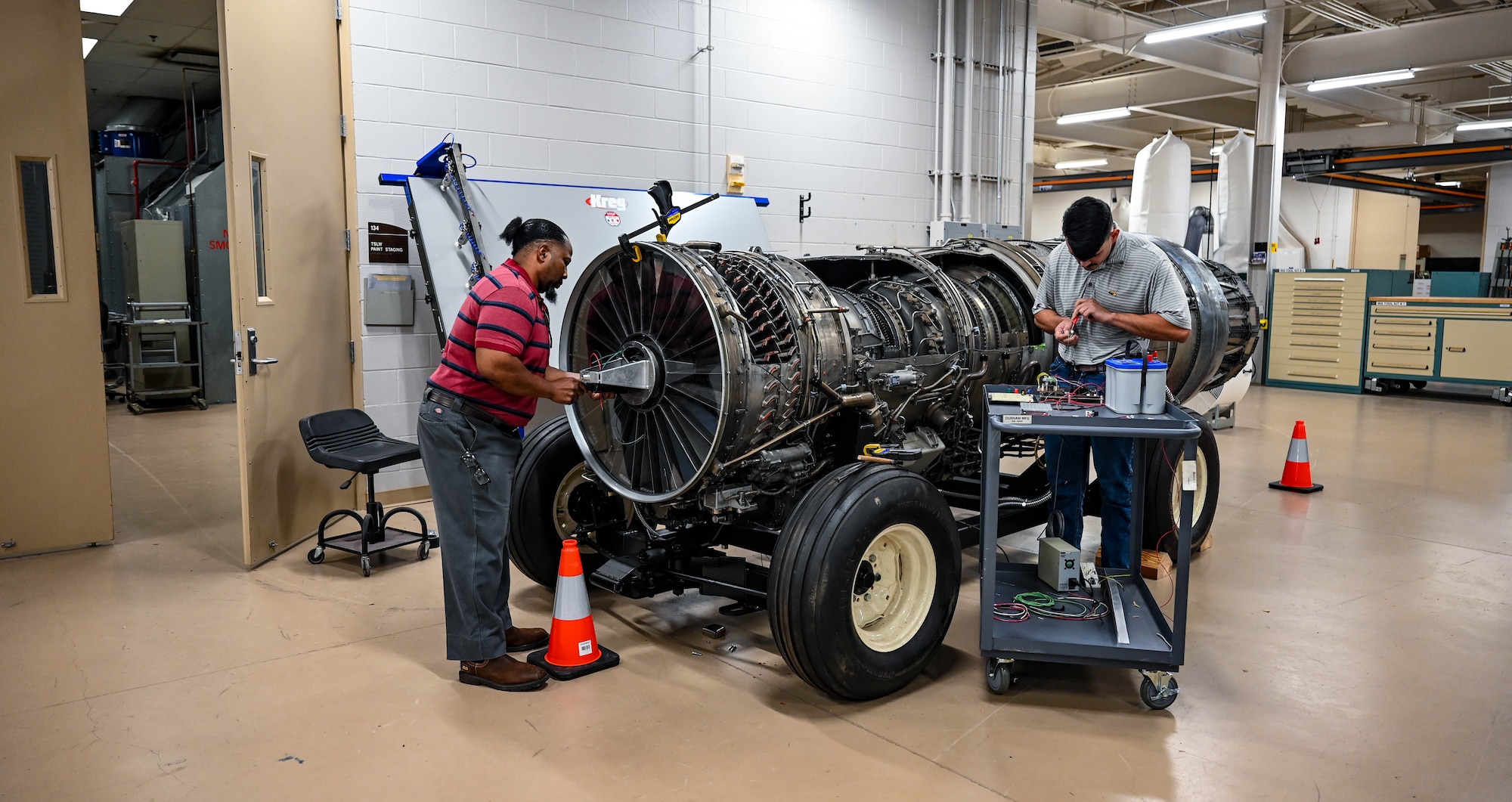Two men work on a plane engine display