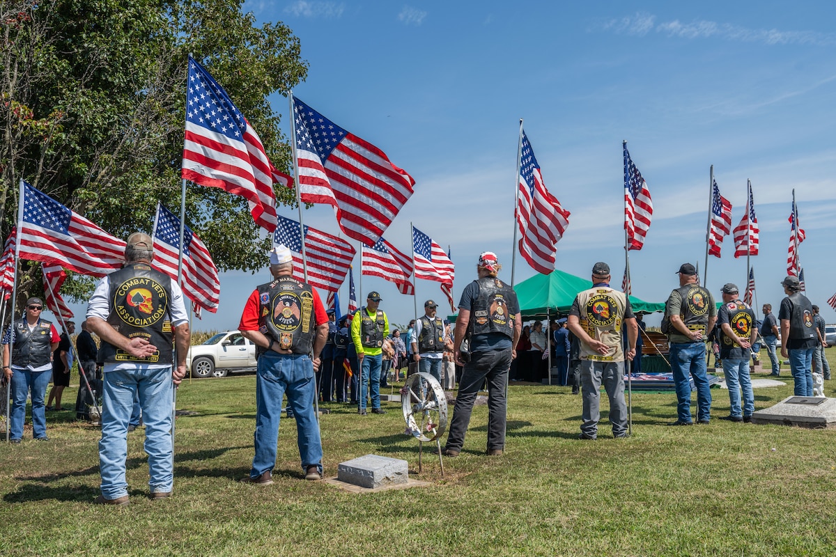 A group of people stand in a line with American flags in their hands.