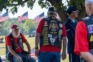 A group of men in leather vests stand in a group.