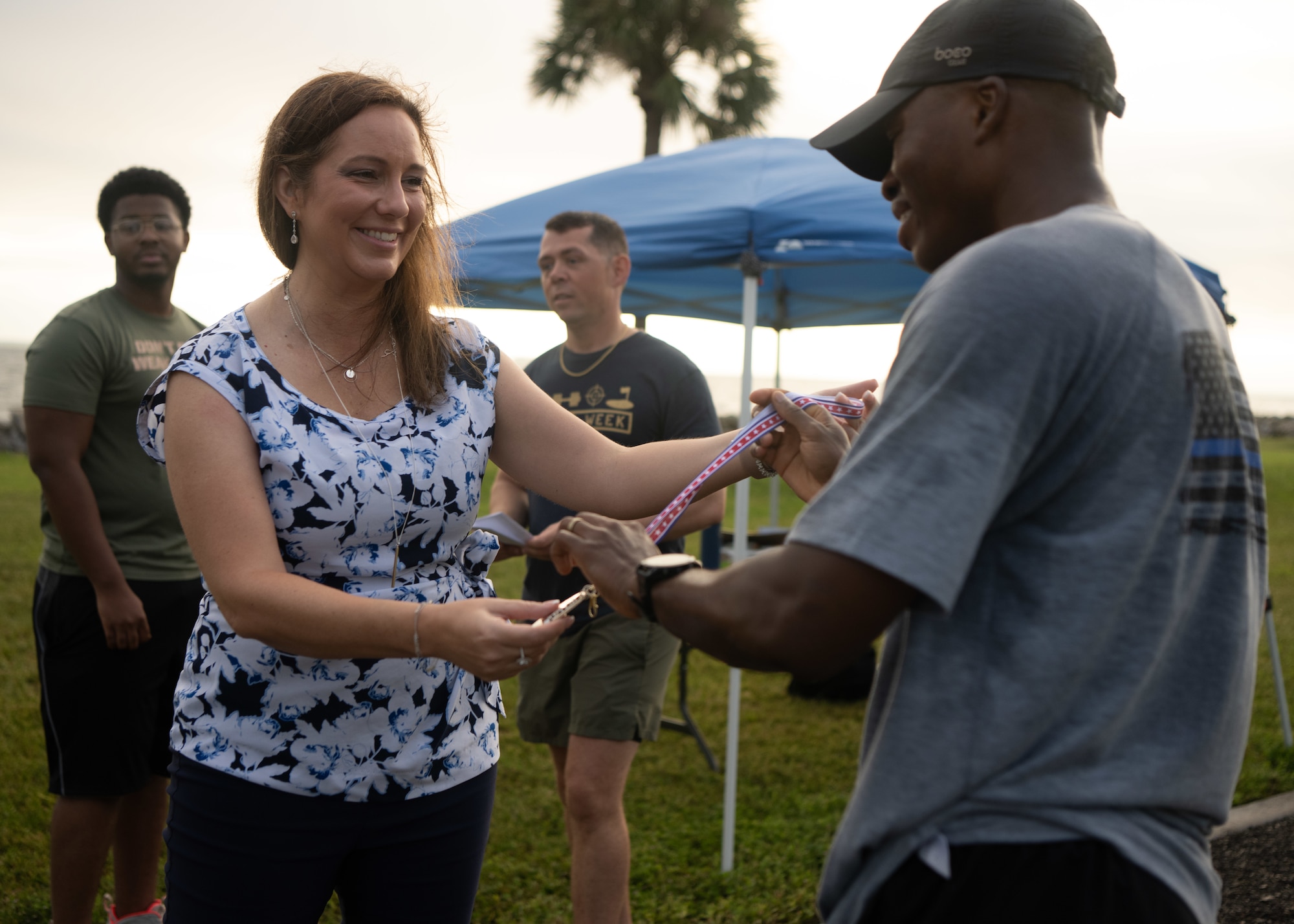 Jeanne Rhea-McManus, 1st Lt. Joseph D. Helton Jr.’s sister, awards the 2nd place medal to Ansumana Turay, Office of Special Investigations Detachment 340 special agent, following the 16th annual Helton Hall 5K  held at MacDill Air Force Base, Florida, Sept. 8, 2025. The 5K honors her brother who extended his deployment to continue leading missions near Baghdad and was killed by an improvised explosive device on Sept. 8, 2009. Helton was the first security forces officer killed in military operations since the Vietnam War. (U.S. Air Force photo by Airman 1st Class Helen Ly)