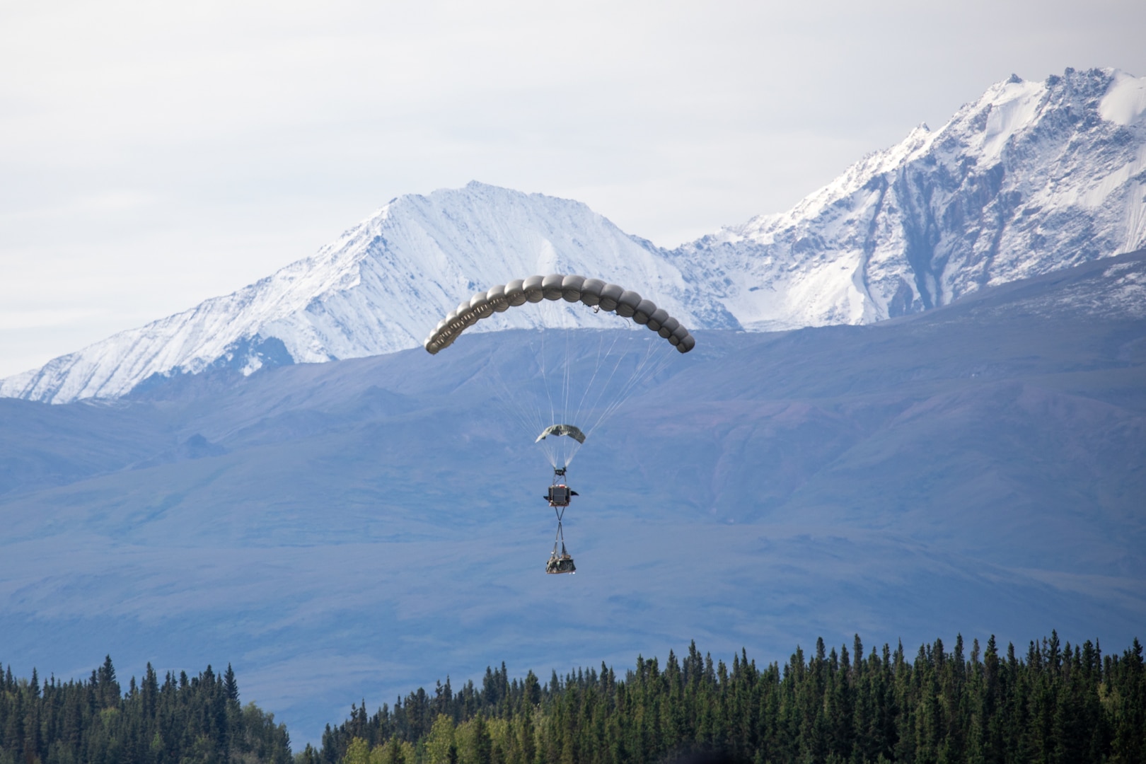 Group of people observe a parachute fall from the sky