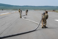 U.S. Airmen assigned to the 27th Special Operations Wing run a hose down a runway to perform a forward arming and refueling point training (FARP)