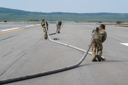 U.S. Airmen assigned to the 27th Special Operations Wing run a hose down a runway to perform a forward arming and refueling point training (FARP)