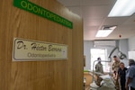 A door with a name plate of a Panamanian doctor is slightly ajar while service members and doctors are seen in the background