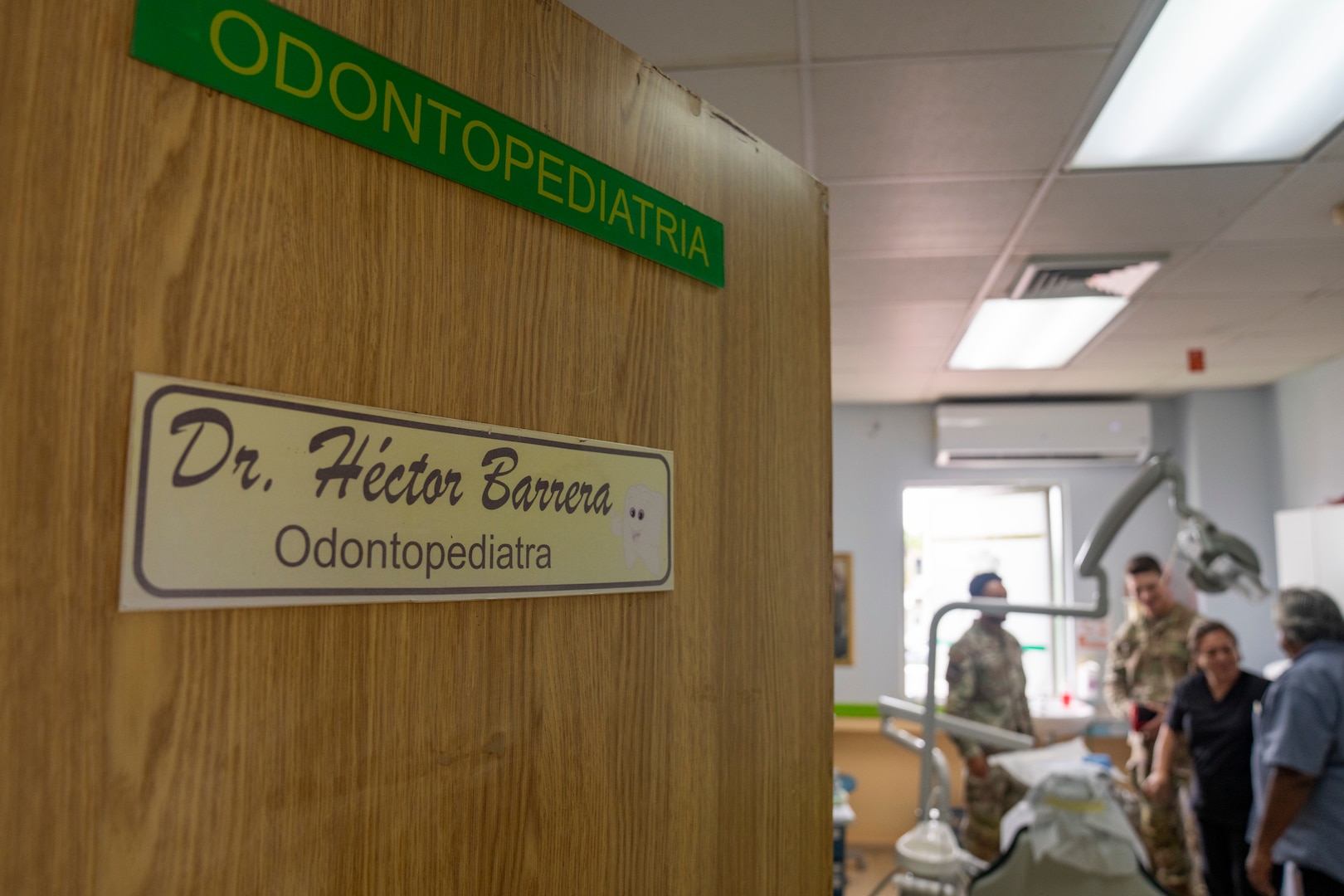 A door with a name plate of a Panamanian doctor is slightly ajar while service members and doctors are seen in the background
