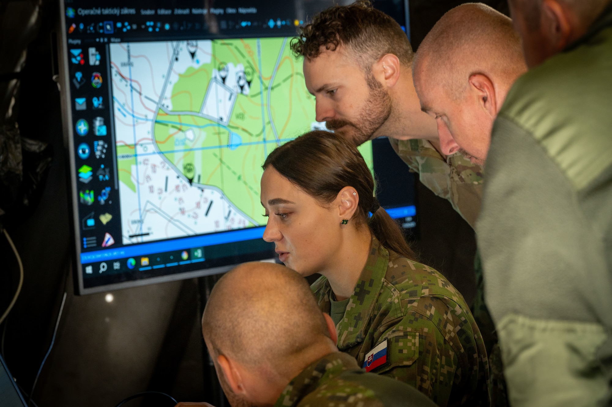 Members of an allied EOD team look at a computer screen.