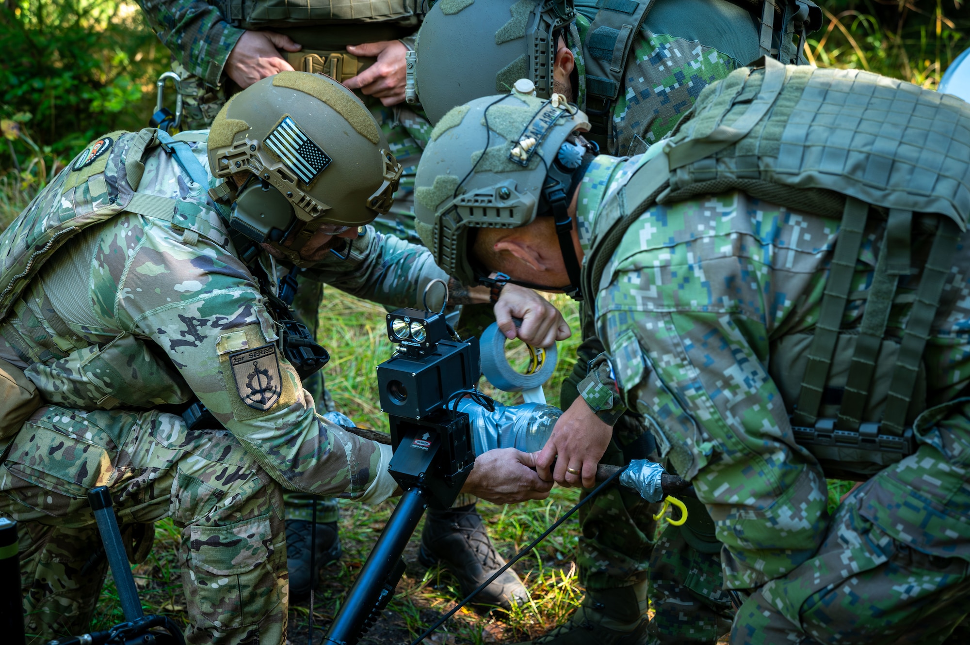 An Airman wraps duct tape around a bottle with members of the Slovak Armed Forces.